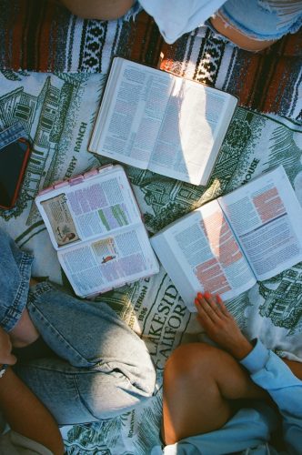 People reading open books on a blanket